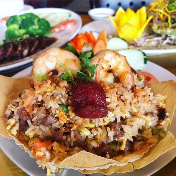 Vietnamese fried rice with shrimp and a red garnish, served in an edible bowl.
