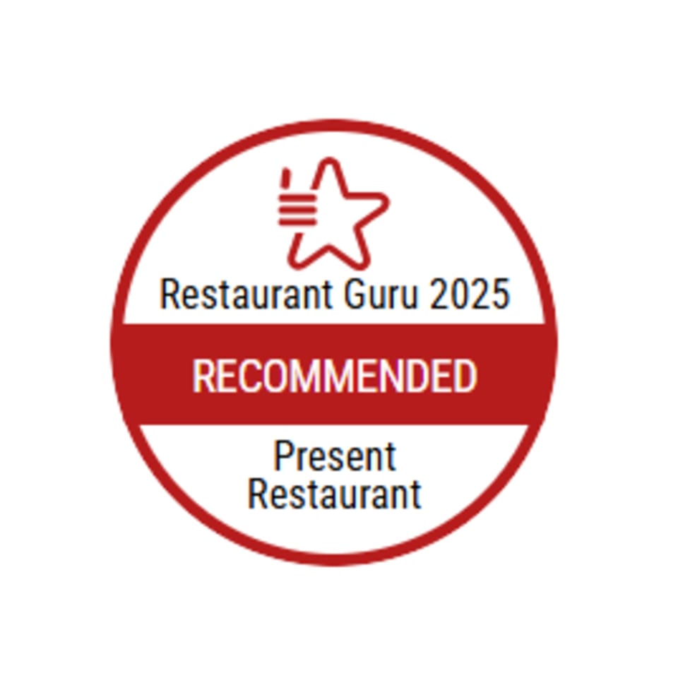 Restaurant Guru 2025 Recommended badge for Present Restaurant, a red and white circular logo.