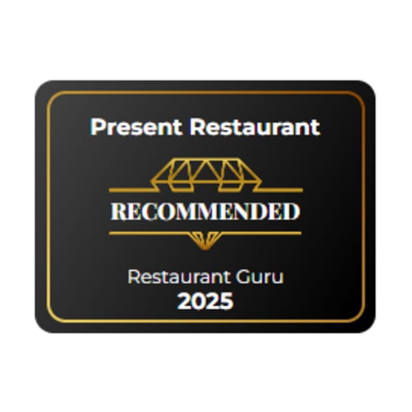 Present Restaurant's black and gold "Recommended by Restaurant Guru 2025" badge.