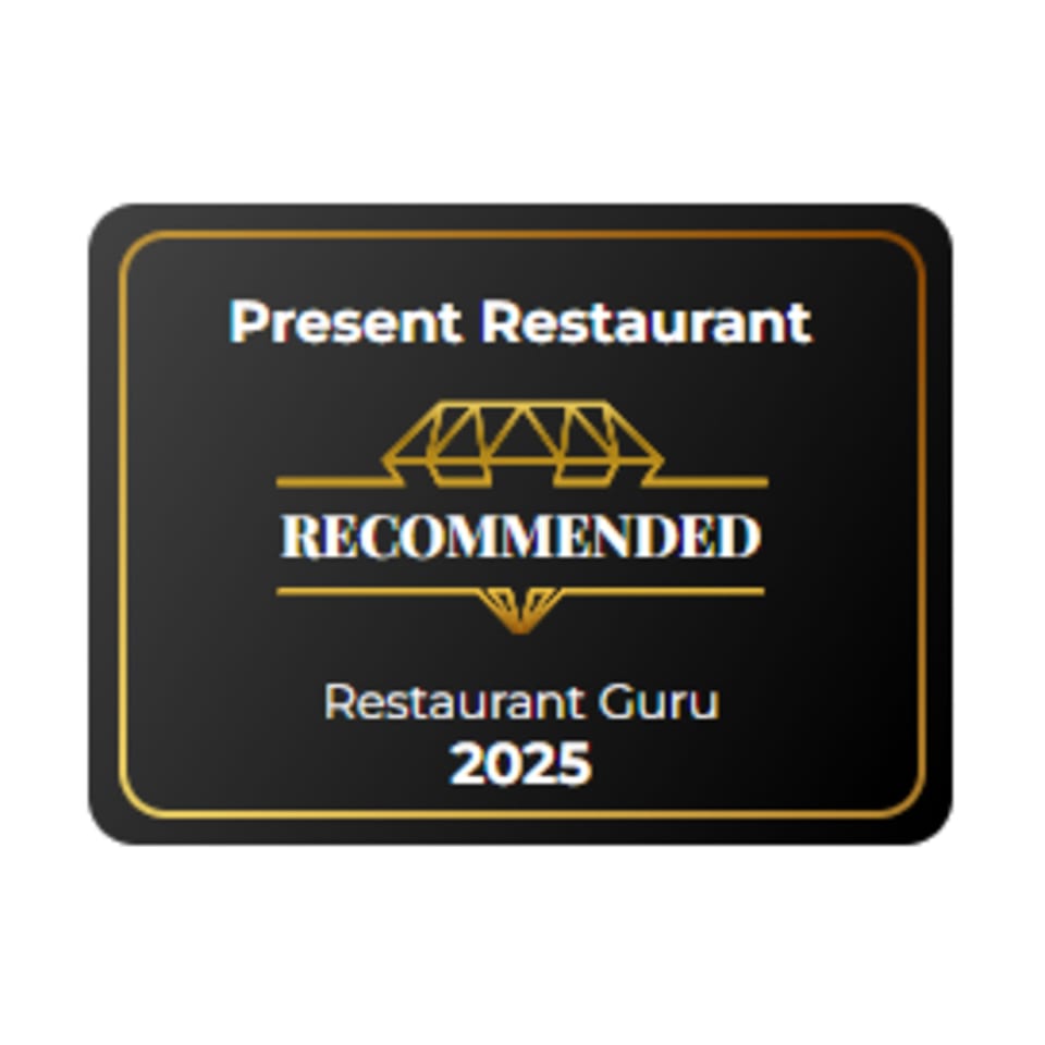 Present Restaurant's black and gold "Recommended by Restaurant Guru 2025" badge.